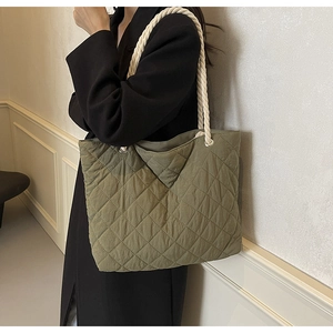 Olive green quilted tote bag with white rope handles shown from a side shoulder view