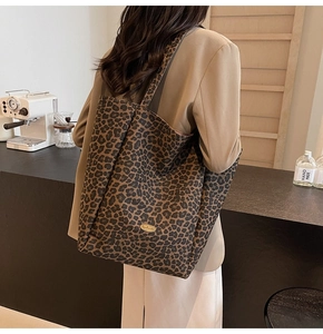 Detailed close-up of large leopard print velvet tote bag with oval metal logo plaque