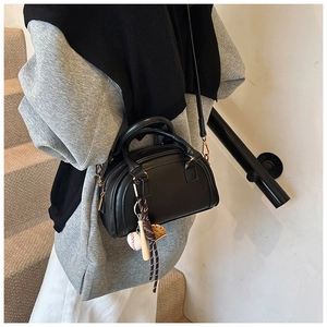 Detail einer schwarzen PU-Leder-Bowlingtasche mit Reißverschluss und Baseball-Anhänger
