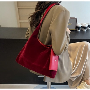 Detail of burgundy velvet tote bag with matching leather strap and small clip-on pouch