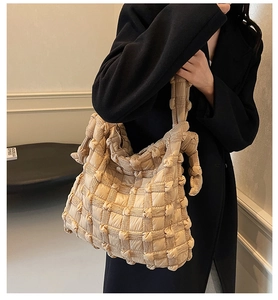 Gros plan du sac fourre-tout en tissu matelassé beige et de la poignée rembourrée souple