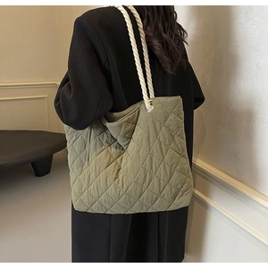 Olive green quilted tote bag with chunky white rope handles shown on a model