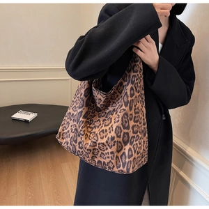 Close-up detail of leopard print suede shoulder tote bag styled with a black autumn coat