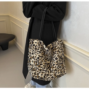 Detail of a large quilted leopard print tote bag with black straps on a fashion model