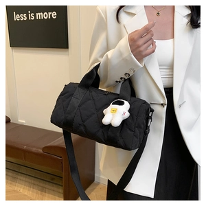 Detail of black quilted barrel bag featuring astronaut charm and nylon texture