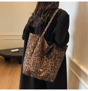 Detail of leopard print velvet tote bag with wide shoulder strap and handmade metal badge