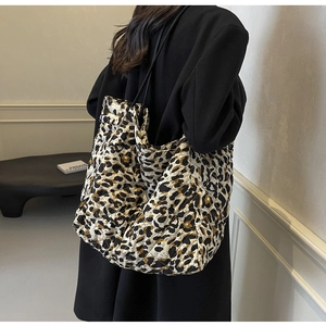 Detail of leopard print quilted tote bag with drawstring straps on a fashion model