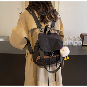 Détail d'un sac à dos en nylon noir avec broderie et breloque de monstre en peluche