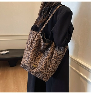 Detail showing high-capacity leopard print tote bag with a golden metal logo plaque