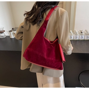 Detail of burgundy velvet tote bag with matching pouch shown on a model's shoulder