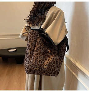 Close-up of a large leopard print velvet tote bag featuring a golden oval brand plaque