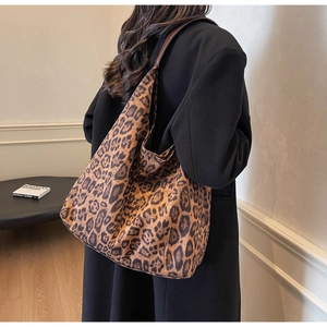 Close-up of a large leopard print suede tote bag paired with a classic black winter coat