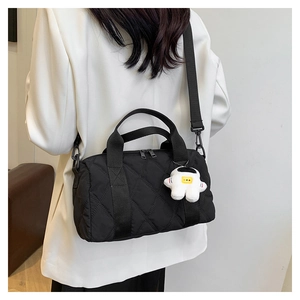 Quilted black nylon crossbody bag with astronaut charm shown on a white blazer