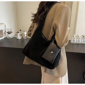 Detail of black faux suede shoulder bag with detachable mini pouch on a model