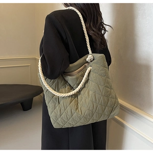Detail view of grass green quilted tote bag with white thick rope straps and nylon texture