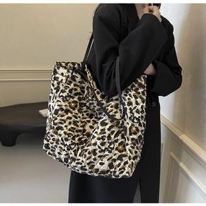 Model view of a large leopard print quilted tote bag worn as an underarm shoulder bag