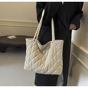 Detail of cream quilted tote bag featuring stylish braided rope handles for women