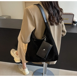 Detail of black suede hobo shoulder bag with matching mini pouch on a female model