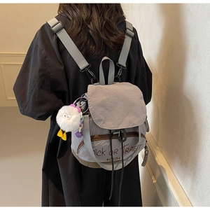 Gros plan d'un sac à dos en nylon gris avec imprimé Trick or Treat et breloque peluche