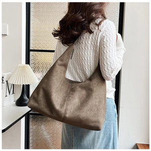 Brown suede hobo bag shown on shoulder with high capacity and soft texture
