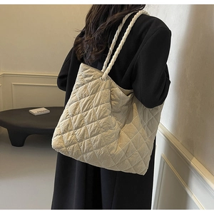 Detail of beige quilted tote bag featuring a decorative white rope shoulder strap for women