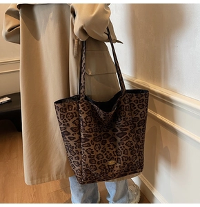 Detail view of large leopard print tote bag in velvet fabric with golden metal logo tag