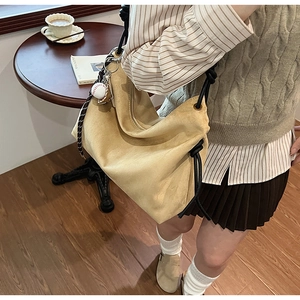 Détail du sac hobo en daim avec bandoulière en corde épaisse et pendentif baseball