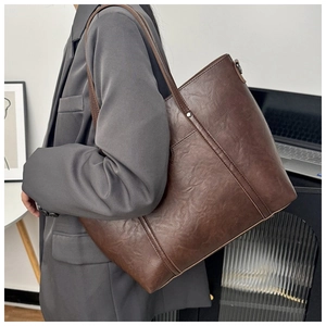 Détail du grand sac cabas vintage en cuir marron porté par un mannequin pour le bureau