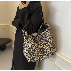Detail of leopard print quilted tote bag worn with a black coat for stylish casual look