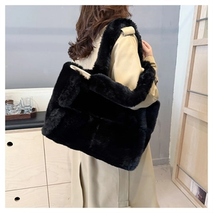 Gros plan d'un sac cabas en fausse fourrure noire porté avec un trench-coat beige