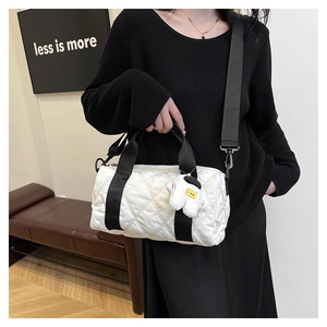 Detailed shot of white quilted nylon boston bag with astronaut charm and black strap