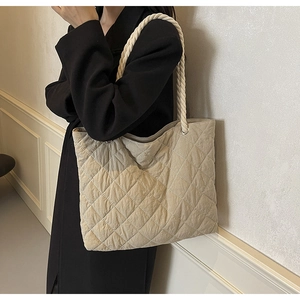 Detail of beige quilted tote bag featuring creative thick rope handles and soft texture