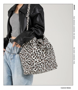 Detail of a large leopard print canvas tote bag styled with a casual leather jacket outfit