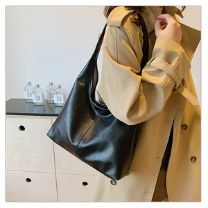 Detail of a vintage black cracked leather hobo bag showing texture and drape on a model