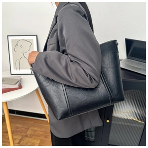 Gros plan d'un grand sac cabas en cuir huilé noir rétro porté à l'épaule pour femme