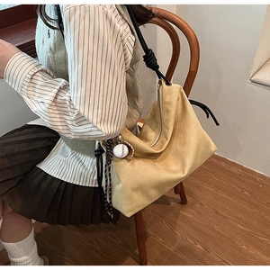 Détail du sac à bandoulière en daim kaki avec bandoulière en corde et breloque baseball