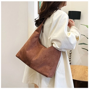 Close-up of brown matte suede Hobo shoulder bag worn by model in a cozy interior