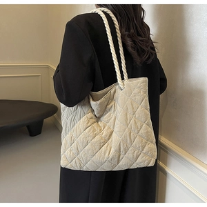 Detail of beige quilted tote bag featuring a white thick rope handle for women