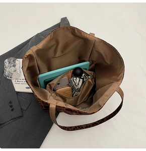 Detail view of spacious leopard print tote interior holding a tablet and daily items