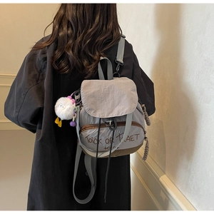 Détail d'un sac à dos en nylon gris et marron avec broderie et porte-clés canard blanc