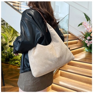 Chic beige faux suede hobo bag with dark brown leather strap worn by a model in soft light