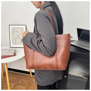 Sac fourre-tout vintage en similicuir marron porté par un mannequin dans un bureau chic