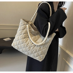 Detail of beige quilted tote bag with thick cotton rope straps and rhombic pattern texture