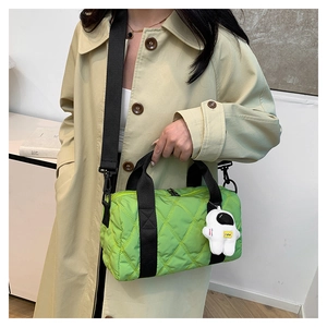 Detail of green quilted nylon cylindrical handbag with white astronaut charm and strap