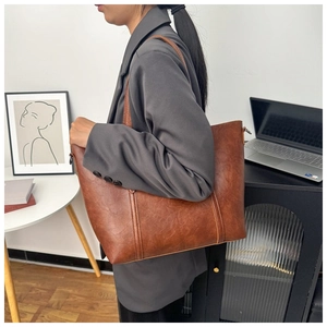 Détail du grand sac cabas marron vintage porté par un mannequin dans un bureau minimaliste