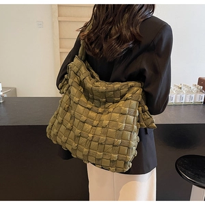 Détail du grand sac cabas matelassé tressé vert olive porté à l'épaule par un mannequin