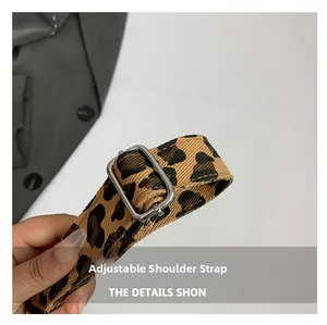 Detail of adjustable leopard print canvas strap with silver metal buckle on a shoulder bag