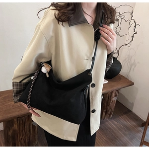 Détail du sac bandoulière en toile noire avec bandoulière nouée et pendentifs mignons