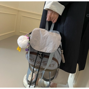 Détail du sac à dos gris-bleu en nylon avec cordon, breloque poussin et texte imprimé