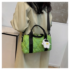 Model wearing a vibrant green quilted nylon crossbody bag with astronaut charm